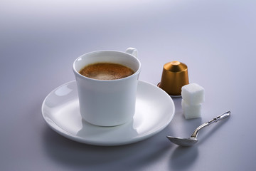 Studio shot of a cup of expresso coffee with coffee capsules and sugar lumps.