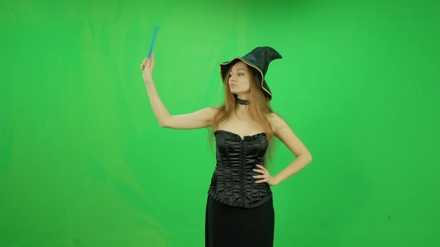 Funny witch with hat and magic stick casting spells green screen