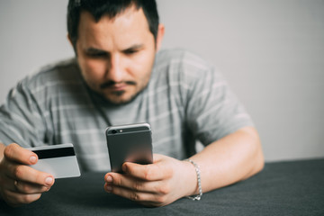 Cropped picture of man with credit card white pattern and phone