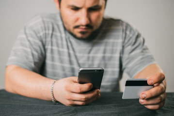 Cropped picture of man with credit card white pattern and phone