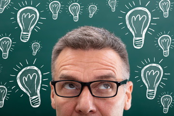 Mature Man Looking Up With Creative Light Bulb Drawn