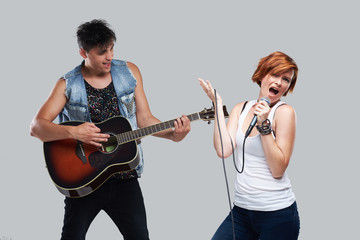 Musical artists sing and play acoustic guitar. Contemporary cover band. Isolated over grey background. Woman with microphone sing loudly 