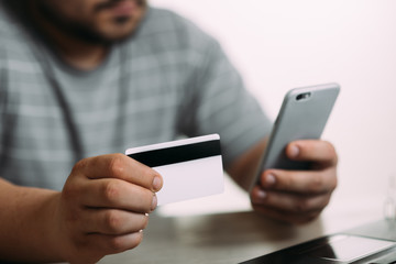 Cropped picture of man with credit card white pattern and phone