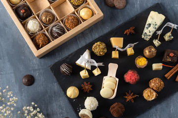 Set of fine chocolate candies and cheese. White, dark and milk chocolate, brie, blue cheese, goat cheese and parmisan on the plate. Chocolate cheese plate, top view