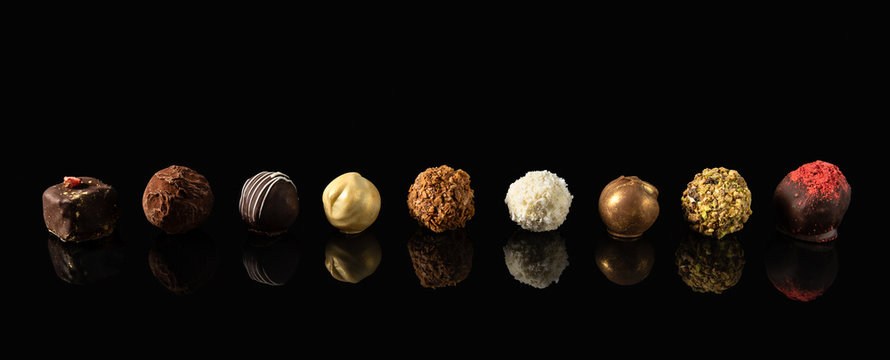 Set of fine chocolate candies White, dark and milk chocolate on black background with reflection