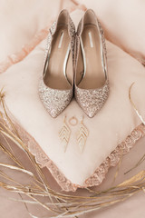 Blush pink bridal shoes and accenting jewelry with gold floral decoration. Pink background. Close up and top view. 