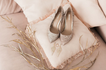 Blush pink bridal shoes and accenting jewelry with gold floral decoration. Pink background. Close up and top view. 