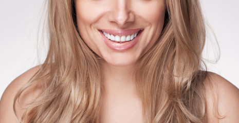 Adult beautiful blond woman with white veneers on the teeth.