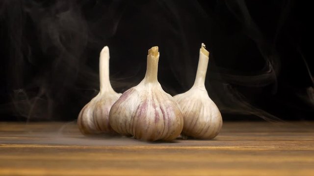 Fresh garlic on a black background that blows cold and fresh, close-up, slow mo, vegetables