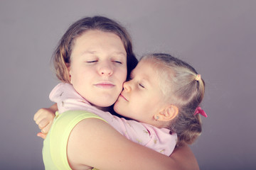 Two sisters hug each other.