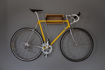 Ein geles Fahrrad an einer Halterung an einer grauen Wand in der Wohnung.