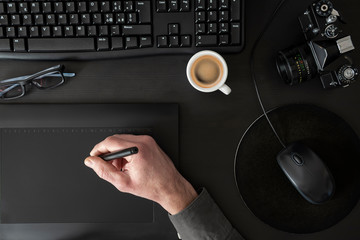 Designer drawing on graphic tablet on black desk