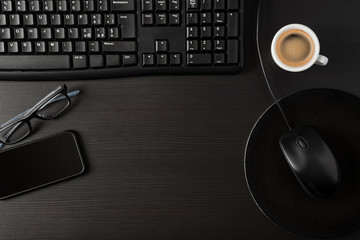 Total black desk with cup of coffee, pc and personal items