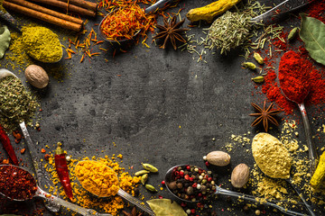 Set of various spices in spoons on black background.