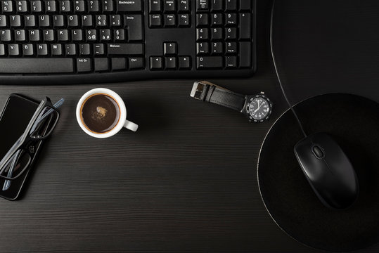 Total black desk with cup of coffee, pc and personal items