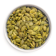 Raw pumpkin seeds in bowl isolated on white background. top view