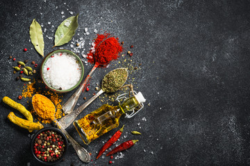 Spices and olive oil on black stone background.