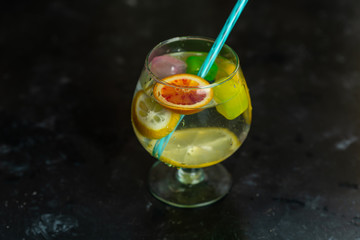 Refreshing, cold drink in a glass with colorful ice cubes and slices of citrus fruit