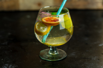 Refreshing, cold drink in a glass with colorful ice cubes and slices of citrus fruit
