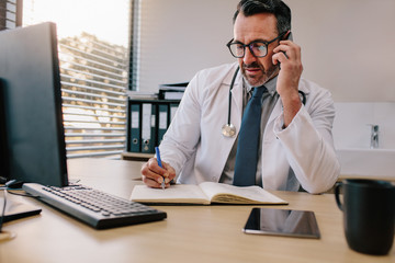 Doctor talking on phone and making notes