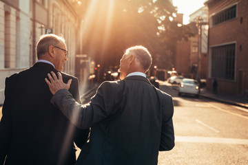 Two senior business people walking outdoors