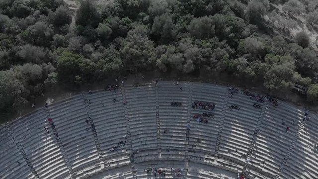Moving above and away from the platforms and reaching the scene of the ancient theater of Epidavros in Greece. Clear sky, sunny weather, flat colour profile.