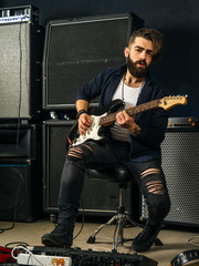 Bearded man playing guitar in a music studio