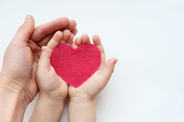Adult and child hands holding red heart. Health care, donate and family insurance concept, world...