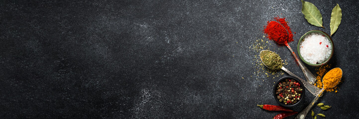 Spices, sea salt and pepper on black stone background.