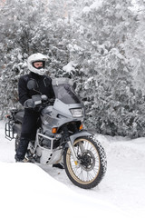 Naklejka premium Rider man is sitting on adventure motorcycle. Winter fun. snowy day. motorbike and snow. Enduro. off road dual sport travel tour, active life style concept. winter clothes, equipment, vertical photo