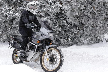 Rider man on adventure motorcycle. Winter fun. snowy day. the snow under the wheels of a motorbike. Enduro. off road dual sport travel tour, active life style concept. winter clothes, equipment