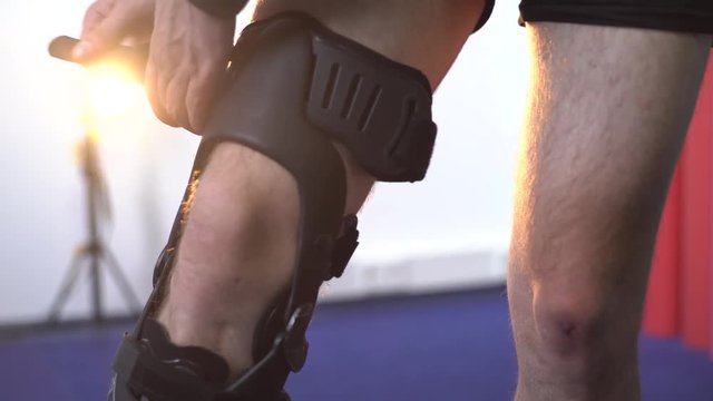 Detail of the lower half of man adjusting a supportive leg brace. Close-up shot