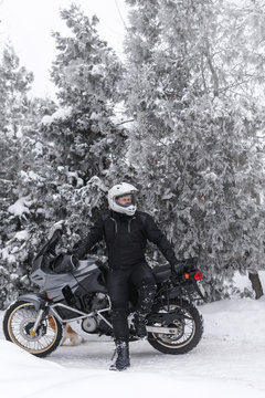 Rider man is sitting on adventure motorcycle. Winter fun. snowy day. motorbike and snow. Enduro. off road dual sport travel tour, active life style concept. winter clothes, equipment, vertical photo