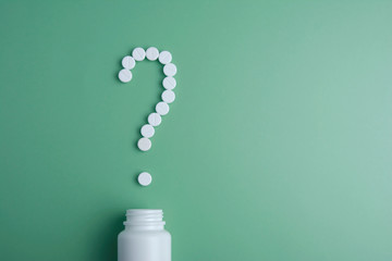 health problem concept with white pills arrange to question mark Question mark made of white pills on green background. What medicines to choose better, what will help. Copy space.