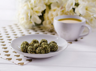 Healthy homemade chocolate energy balls on whtite plate with flower decor on wooden table.