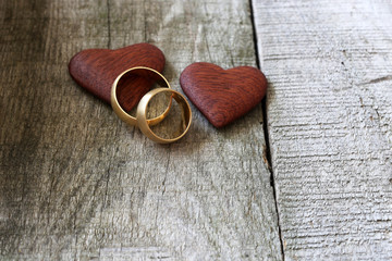 Wedding rings and red heart on wooden background