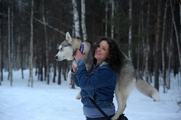 Woman caresses the Husky dog in winter snowy cold day.
