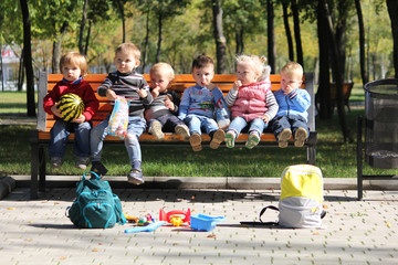 Six babies sitting in urban green nature park on the bench