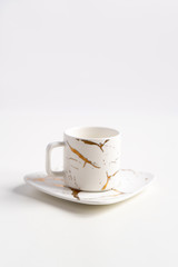 White mugs with a saucer. Cups for coffee and tea on a white background. Utensils for any holiday, luxury wedding, birthday or party. Style Japanese art of repair broken dishes, kintsugi. Gold streaks