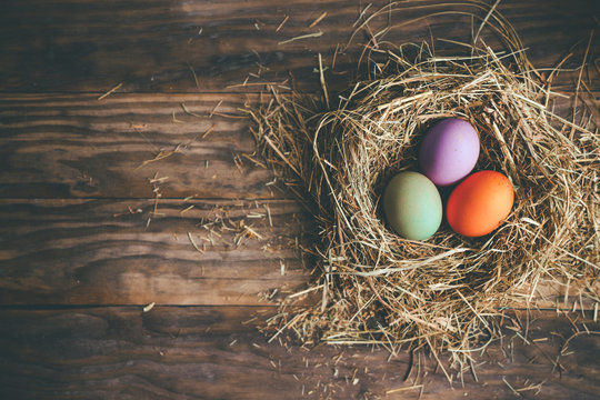 Easter eggs in hay nest on a rustic wooden background