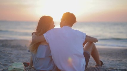 ODESSA /UKRAINE - JULY 12 2018: Slow motion backside view young man hugs girl on Burberry plaid against pictorial sunset near blue sea on July 12 in Odessa 
