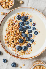 Top view on healthy breakfast, a bowl with organic granola, chocolate pieces, fresh blueberries, hazelnuts and soya milk.