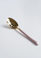 New luxury Golden cutlery view from above on a isolated white background. Top view. Pink spoon for a festive table for a wedding, birthday or party.
