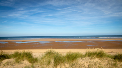 sandy beach blue skies green grass norfolk uk
