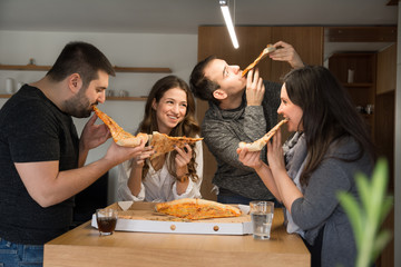 Happy friends having fun while eating pizza