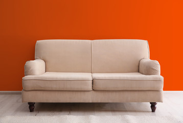 Comfortable sofa in living near orange wall