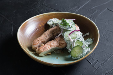 A piece of grilled salmon with cucumbers and Greek yogurt
