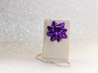 gift with  bow, jewelry and cosmetics for women on  brilliant background.