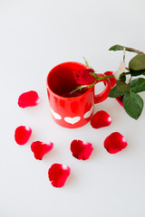 Printed white hearts on red coffee cup and rose isolated on white background