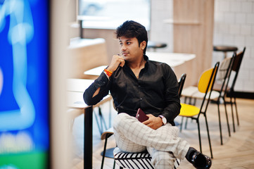 Stylish indian man sitting at fast food cafe and waiting his order.